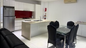Una cucina moderna con isola centrale, elettrodomestici in acciaio inossidabile e zona pranzo con tavolo in vetro e sedie nere.
