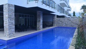 Una casa moderna con piscina, colonne in pietra e un balcone.
