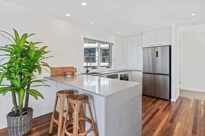 Une cuisine moderne avec un îlot central, des appareils en acier inoxydable et une plante en pot.