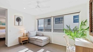 Ein Zimmer mit einem Bett, einem kleinen Sofa, einem Esstisch mit Stühlen, einer Pflanze und einem Fenster mit Blick.