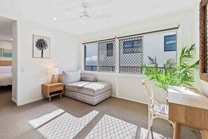 A room with a bed, a small sofa, a dining table with chairs, a plant, and a window with a view. - 8 / 39 Albatross Avenue (Gold Coast)