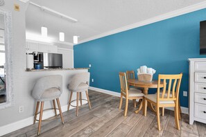 Une cuisine moderne avec des meubles blancs, un réfrigérateur en acier inoxydable et un mur d’accent bleu.