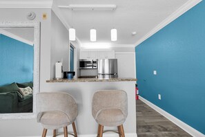 Uma cozinha moderna com armários brancos, eletrodomésticos de aço inoxidável e uma parede azul de destaque.