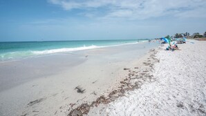 Una playa con cielo despejado, mar tranquilo y algunas sombrillas.