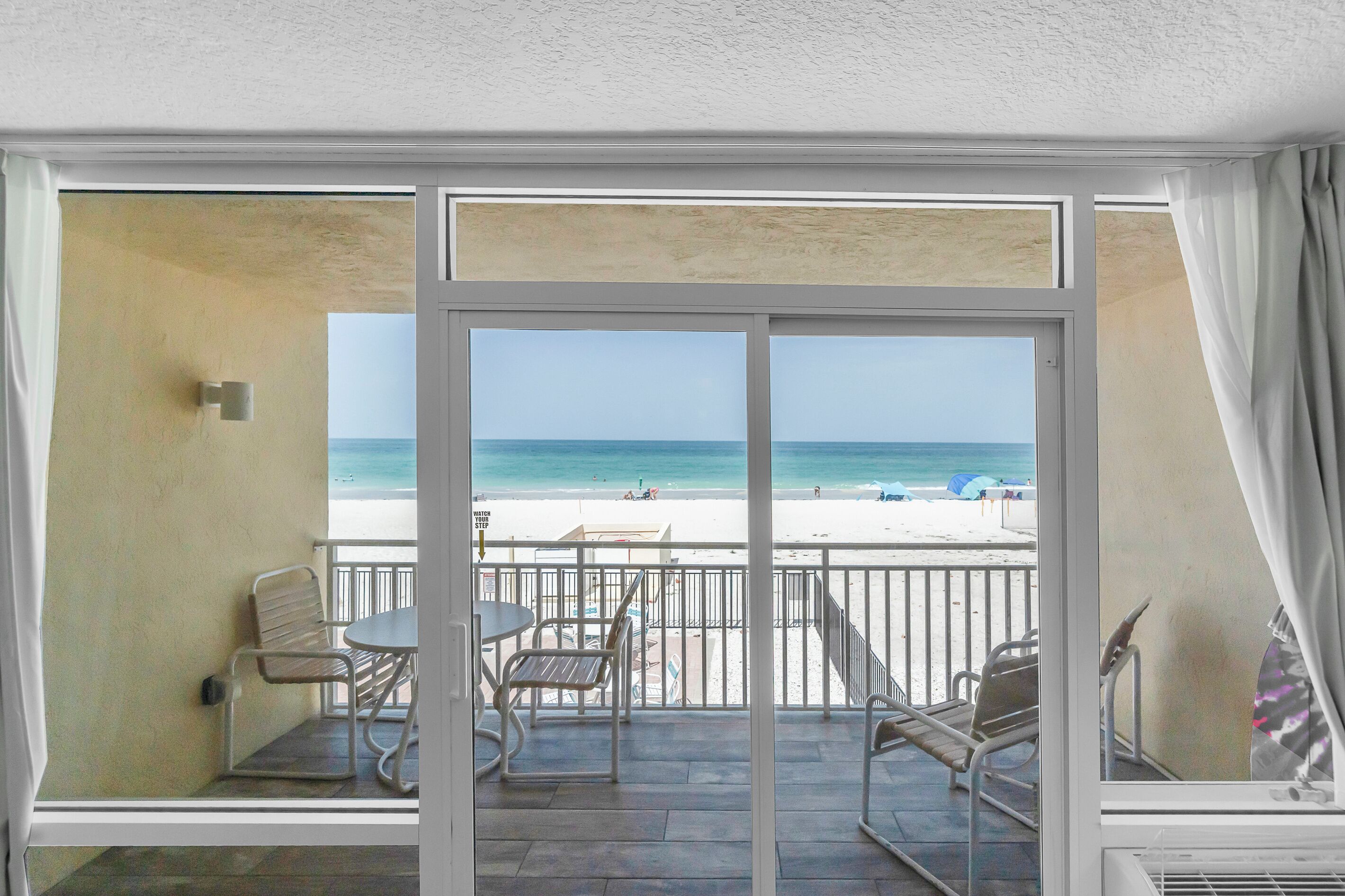 Ein Balkon mit Blick auf den Strand, inklusive Tisch und Stühlen.