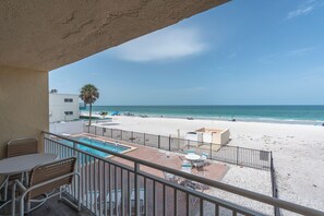 A balcony with a pool, beach view, and outdoor seating. - Beachfront Studio on Anna Maria Island (Bradenton Beach)