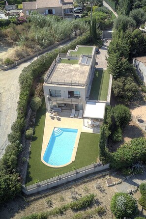 Ein modernes Haus mit Schwimmbad, überdachter Terrasse und gepflegtem Garten.