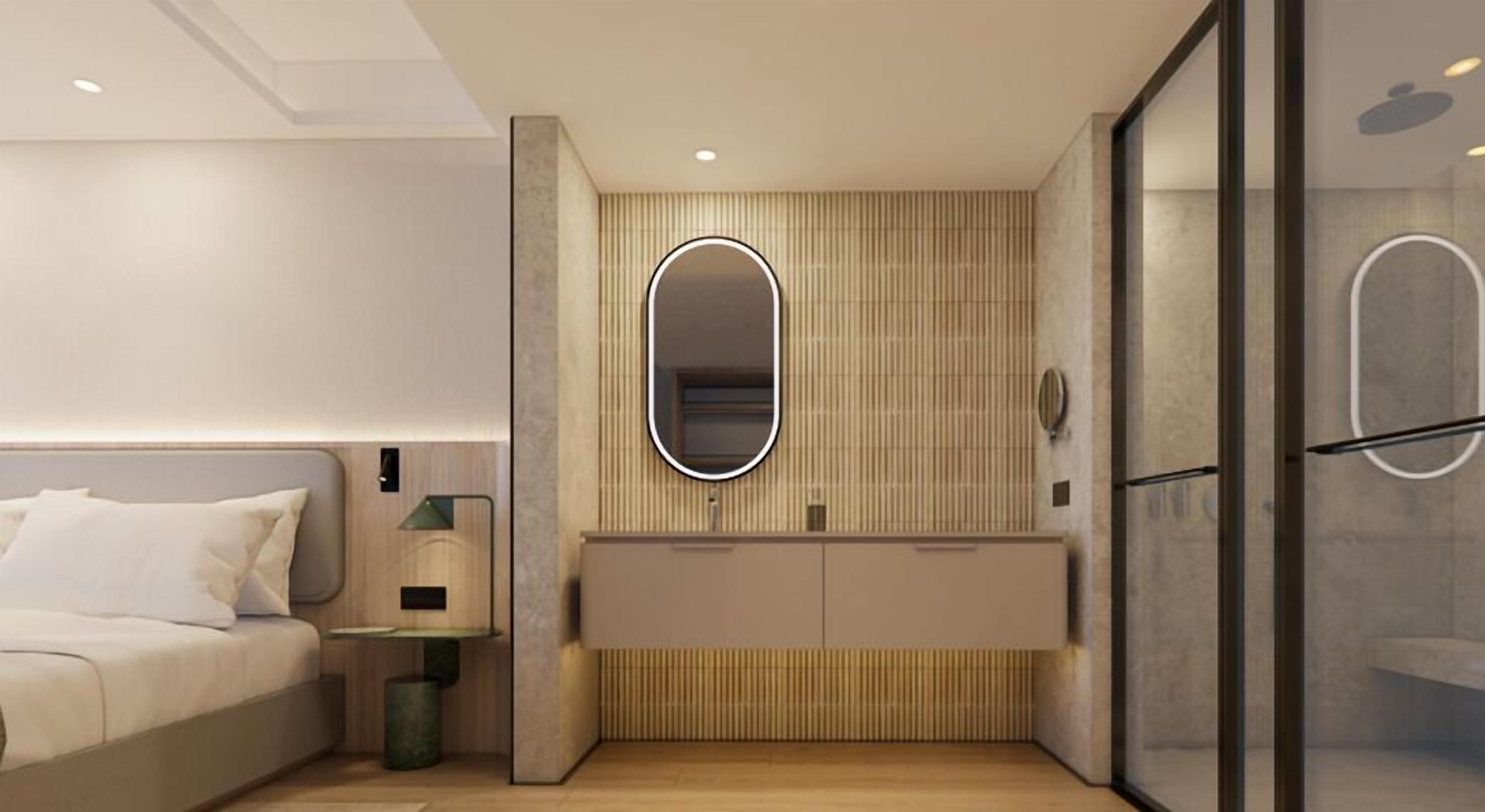 Une chambre d’hôtel moderne, équipée d’un lit, d’une table de chevet et d’un grand miroir.