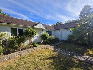 A two-story house with a tiled roof, a front yard with a pathway, and a small garden area.