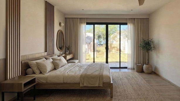 A bedroom with a large bed, a nightstand, a mirror, and a view of the outdoors through a sliding door. - Vikasa Evolution Retreat Phuket (Koh Lon)
