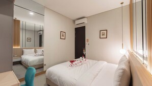 Una habitación de hotel con una cama grande, un espejo, un escritorio y una ventana con cortinas.