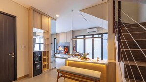 Una cocina moderna con estufa integrada, un área de comedor con banco y una escalera.