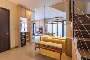 Una cocina moderna con estufa integrada, un área de comedor con banco y una escalera.