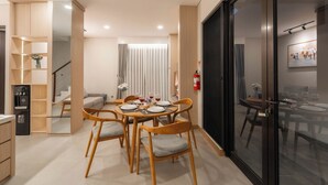 Un área de comedor moderna con una mesa redonda, sillas de madera y un separador de vidrio.