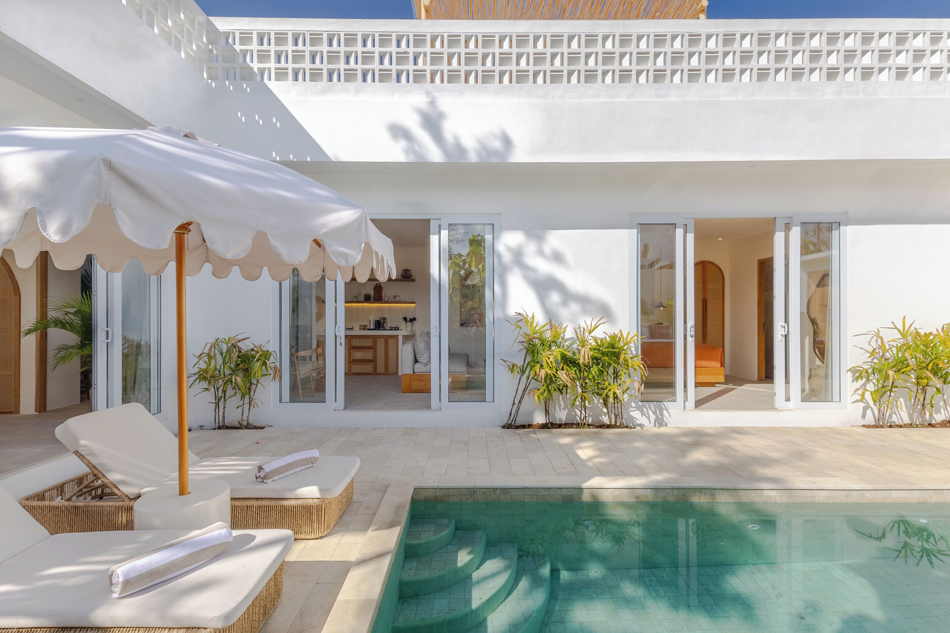 A modern house with a swimming pool, sun loungers, and a covered patio area.