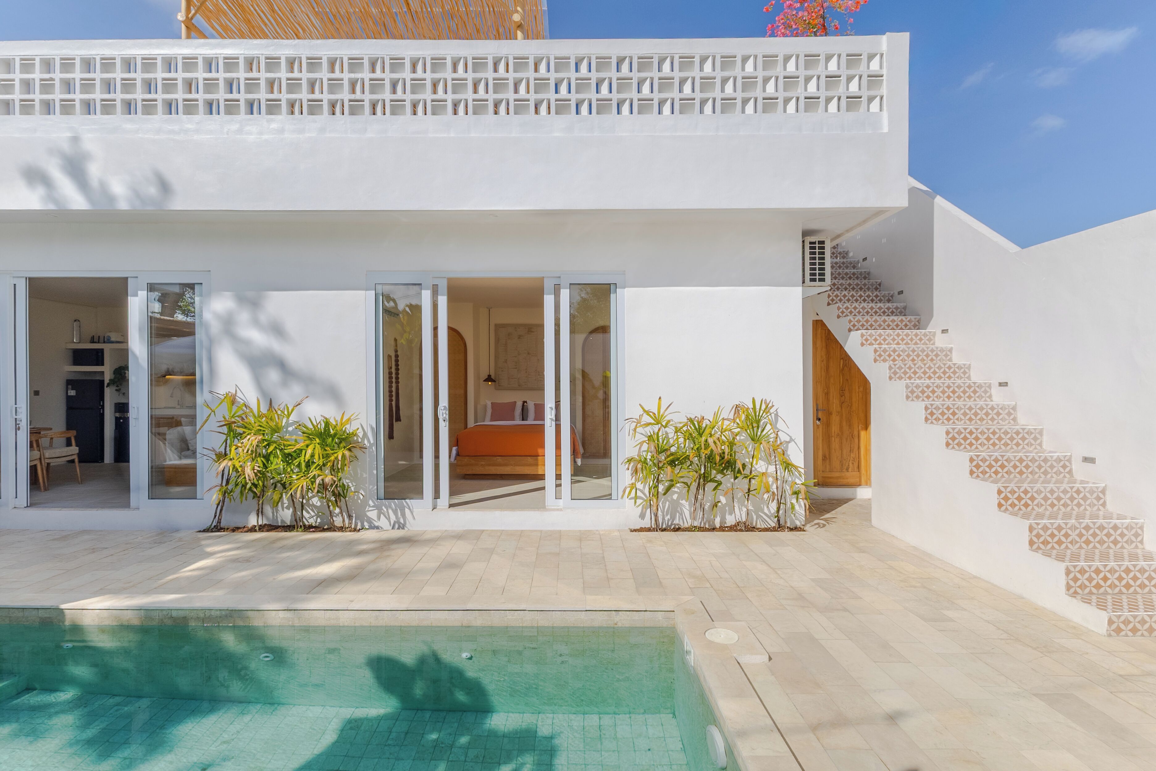 Una casa moderna de dos pisos con piscina, una escalera y un balcón.