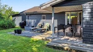 Un portico coperto con mobili da esterno, un barbecue e un piccolo deposito nel giardino.