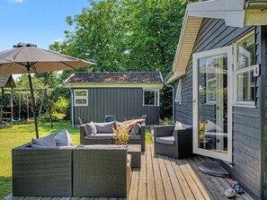 Eine Terrasse mit Korbmöbeln, eine kleine Gartenhütte und die Hausnummer 4.