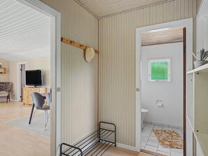Ein Zimmer mit einem Bett, einem Fernseher, einem Sessel und einem Badezimmer mit Fenster.