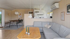 Un soggiorno moderno con tavolino in legno, divano grigio e zona pranzo con tavolo e sedie in legno.