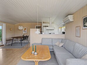 Ein modernes Wohnzimmer mit einem Holztisch, einer grauen Couch und einem Essbereich mit Tisch und Stühlen.