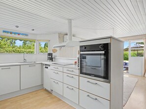 Eine moderne Küche mit weißen Schränken, einem eingebauten Backofen und einem Fenster mit Blick auf Grünflächen.