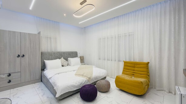 Ein modernes Schlafzimmer mit einem Bett, einem gelben Sessel und einem Kleiderschrank.