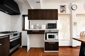 A modern kitchen with built-in appliances, a dining area, and a clock on the wall. - KodoMizu (Shirahama)