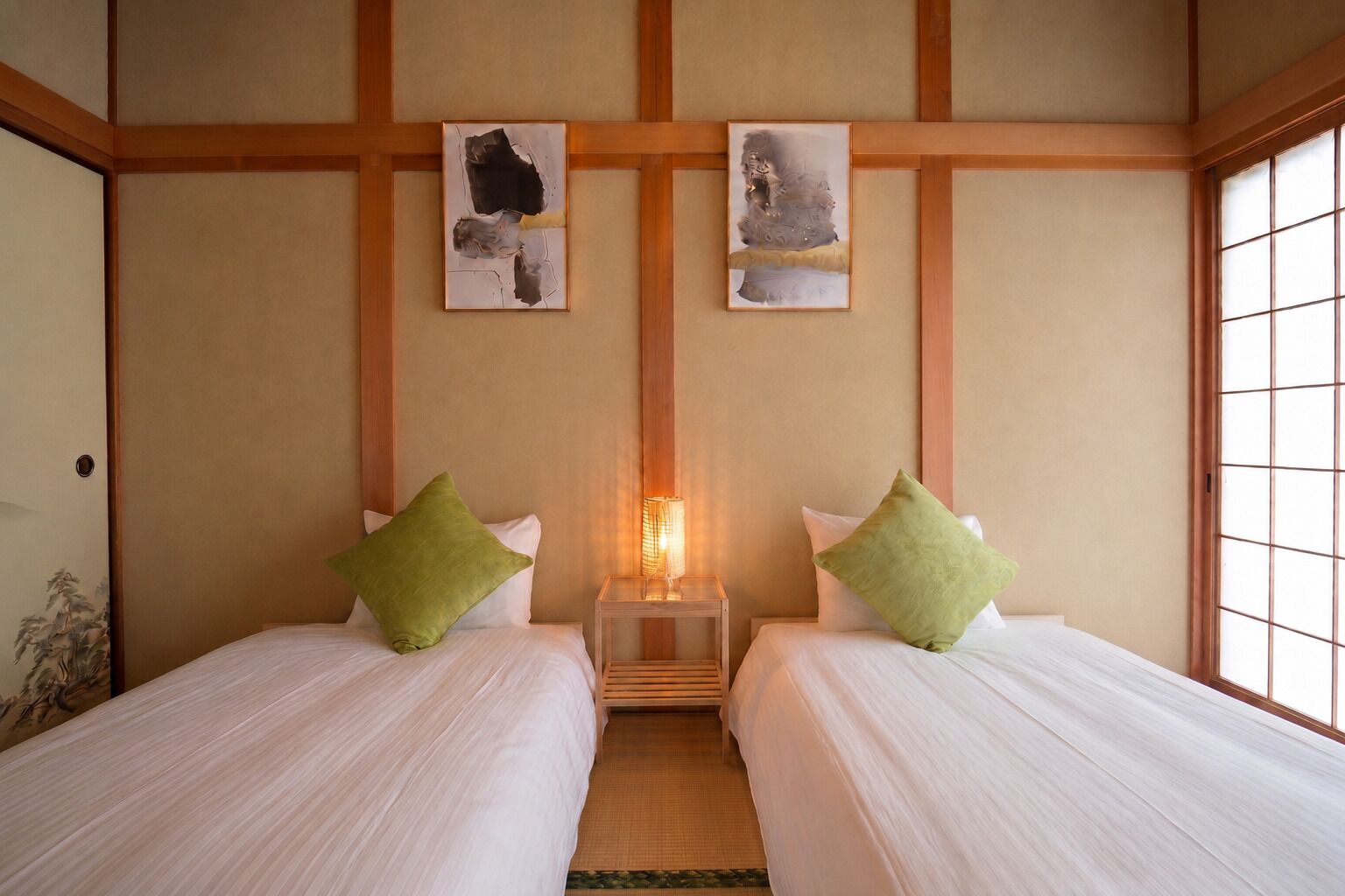 Habitación de hotel con dos camas, una mesita de noche con lámpara y una obra de arte en la pared.