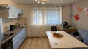A kitchen with a white countertop, a coffee maker, and a dining area with a table and chairs. - Life on the Edge of the Black Forest (Eggingen)