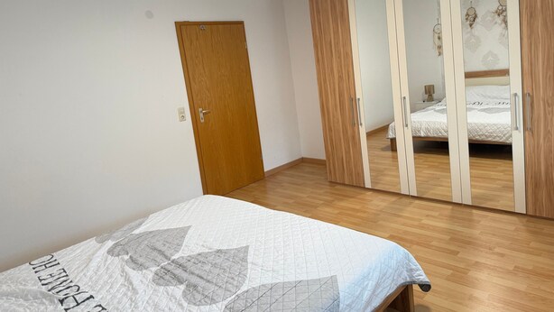A bedroom with a bed, a wardrobe, and a door. - Life on the Edge of the Black Forest (Eggingen)