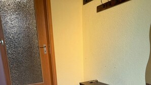 A room with a wooden door, a small table, a bench, and a wall-mounted hookboard. - Life on the Edge of the Black Forest (Eggingen)