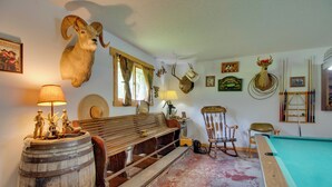 Une pièce avec une table de billard, des meubles en bois et des têtes d’animaux fixées au mur.