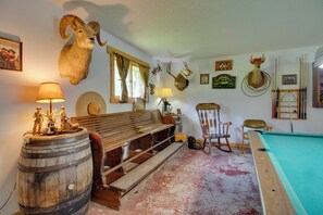 Ein Raum mit Billardtisch, Holzmöbeln und aufgehängten Tierköpfen.