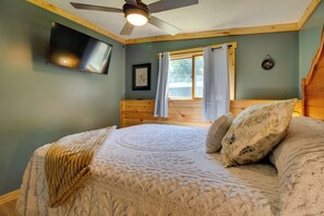 A bedroom with a bed, a ceiling fan, a window with curtains, a mounted television, and a framed picture on the wall. - Cookout Patio w/ Fireplace! Norfork Lake Cabin (Elizabeth)