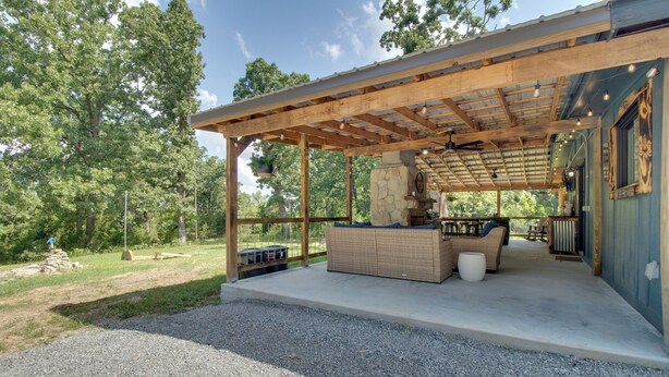 Un espace extérieur aménagé, abrité et doté d’une cheminée en pierre, d’une pergola en bois et d’un chemin de gravier menant à l’entrée.