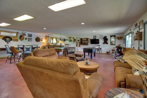 A spacious living room with leather furniture, a fireplace, and various wall decorations including animal heads and a mounted bear head. - Cookout Patio w/ Fireplace! Norfork Lake Cabin (Elizabeth)