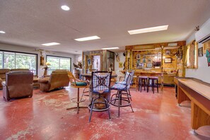 Una stanza spaziosa con pavimento rosso, un'area bar in legno e diversi elementi decorativi.
