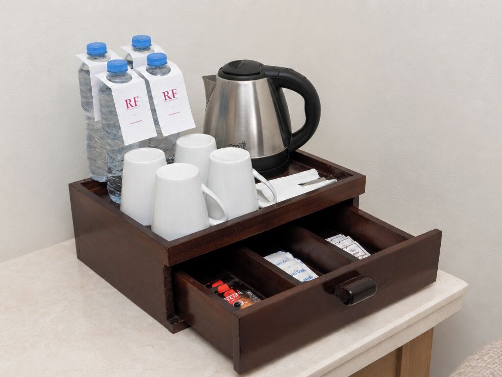 A wooden drawer with a coffee maker, water bottles, and coffee cups.