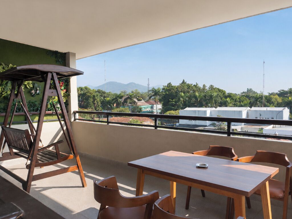 Ein Balkon mit einer Schaukel, einem Tisch und Stühlen.