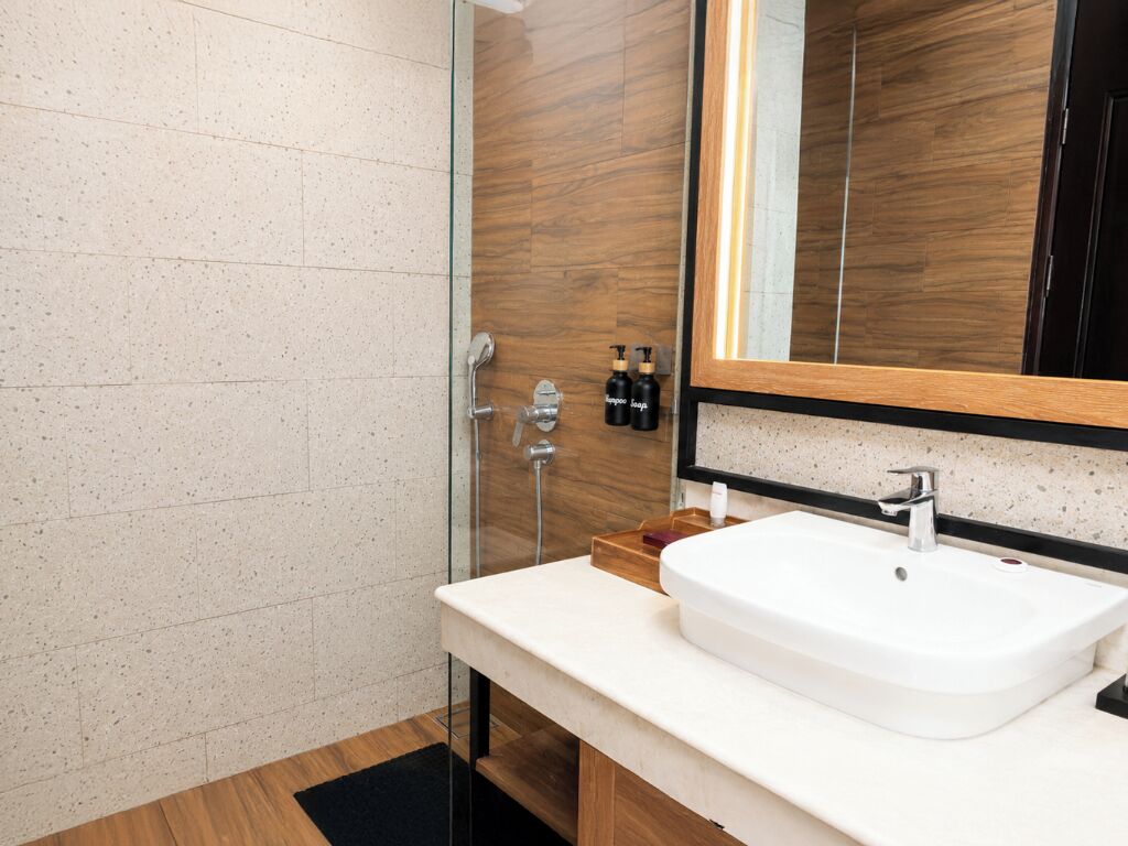 Ein modernes Badezimmer mit einem weißen Waschbecken, einem großen Spiegel und einer Holzvertäfelung.