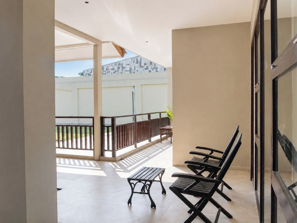 A balcony with a table and chairs, a view of a building, and a glass door.
