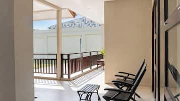 A balcony with a table and chairs, a view of a building, and a glass door.