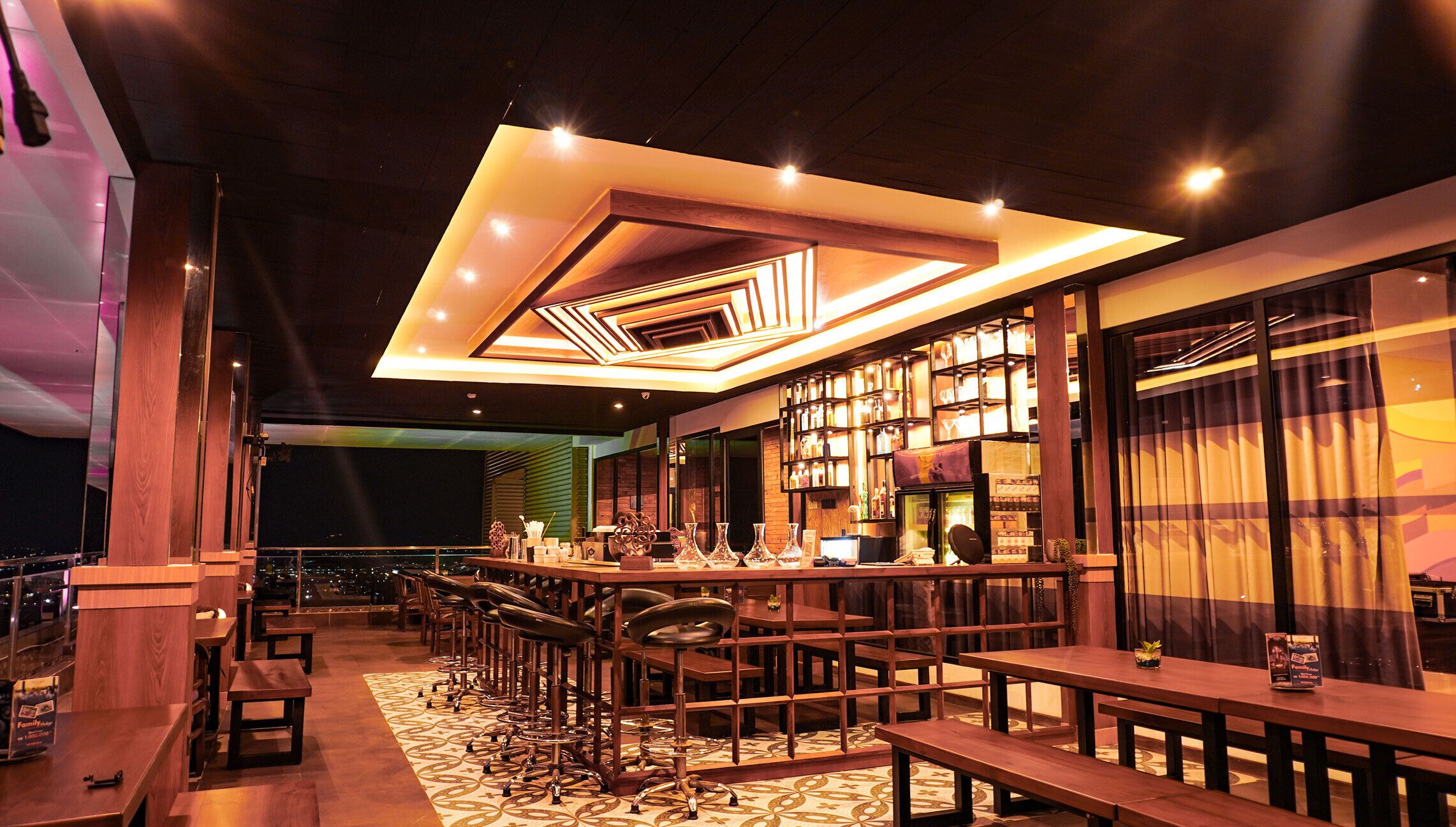 Zona de bar con varias opciones de asientos, incluyendo taburetes y mesas, y un piso con diseño.