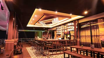 Zona de bar con varias opciones de asientos, incluyendo taburetes y mesas, y un piso con diseño.