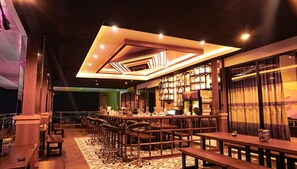 A bar area with multiple seating options, including bar stools and tables, and a patterned floor.