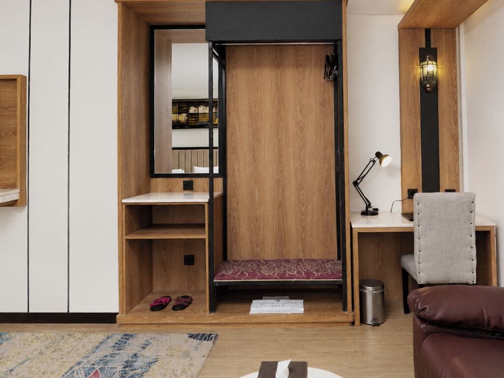Habitación compacta con armario empotrado, un escritorio con silla y una pequeña zona de estar con alfombra.