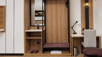 Habitación compacta con armario empotrado, un escritorio con silla y una pequeña zona de estar con alfombra.