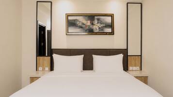 A hotel room with a large bed, two bedside tables, a headboard, and a framed abstract painting on the wall.