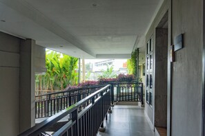 A corridor with a tiled floor, a metal railing, and a view of greenery outside. - Zenith Sunshine (Soreang)